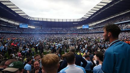 Les supporters de Manchester City fêtent le 8e titre de champion d'Angleterre du club sur le terrain, le 22 mai 2022. (OLI SCARFF / AFP)