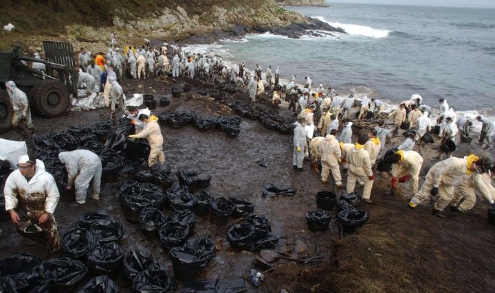 Des personnes s'affairent sur une plage de Figueras (Espagne), souill&eacute;e par la mar&eacute;e noire provoqu&eacute;e par le naufrage du "Prestige", le 15 novembre 2002. (CHRISTOPHE SIMON / AFP)