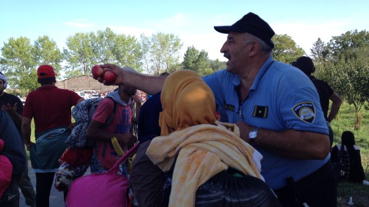 Un policier croate distribue des pommes &agrave; des migrants. (ELISE LAMBERT / FRANCETV INFO)