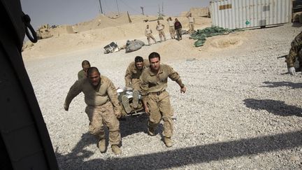 Des Marines évacuent le soldat Louis Madrid, qui souffre de brûlures au premier degré. Il n’a pas été blessé lors d’un combat, mais alors qu’il essayait de mettre le feu à aux ordures d’un camp militaire de la région. (AFP PHOTO / BEHROUZ MEHRI )