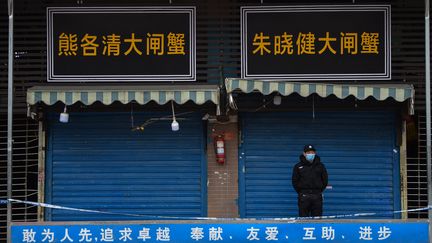 Un&nbsp;agent de sécurité se tient à l'extérieur du marché de Wuhan (Chine), le 24 janvier 2020. (HECTOR RETAMAL / AFP)