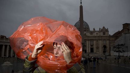 Une femme tente de se prot&eacute;ger de la pluie qui tombe sur la place Saint-Pierre (Vatican), le 18 mars 2013. (ODED BALILTY / AP / SIPA)