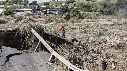 Un homme gravit un pont détruit par les inondations dans le nord de Durban (Afrique du Sud), jeudi 14 avril 2022. (MARCO LONGARI / AFP)