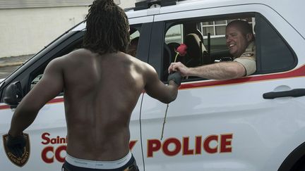 Un habitant de Ferguson (Missouri, Etats-Unis) offre une rose &agrave; un policier, le 19 ao&ucirc;t 2014. (MARK KAUZLARICH / REUTERS)