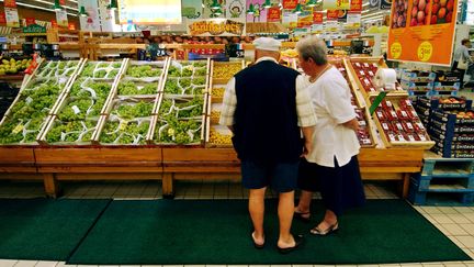 Un couple de retrait&eacute;s fait son choix devant un &eacute;tal de fruits et l&eacute;gumes dans une grande surface du Calvados, en ao&ucirc;t 2004. (MYCHELE DANIAU / AFP)