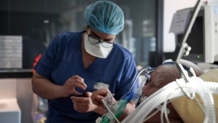 Un membre du personnel soignant de l'hôpital Tenon, à Paris, prend soin d'un patient atteint du Covid-19 en unité de soins intensifs, le 26 janvier 2021. (ALAIN JOCARD / AFP)