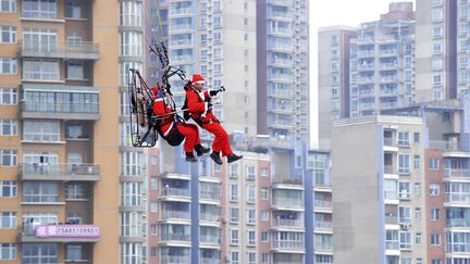 Des membres de l'&eacute;quipe locale de parachute larguent des cadeaux au dessus de Guizhou (Chine) dans le cadre d'une op&eacute;ration promotionnelle, la veille de No&euml;l. (REUTERS)