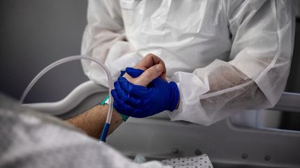 Une infirmière fait la toilette d'un patient infecté par le Covid-19, dans l'unité de soins intensifs de l'hôpital de Lyon-Sud (Rhône-Alpes), le 25 janvier 2021. (JEFF PACHOUD / AFP)