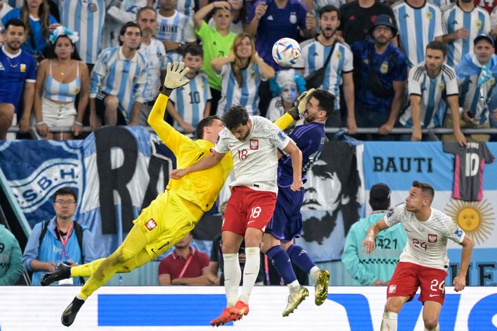 Le gardien de la Pologne Wojciech Szczesny percute le visage de l'Argentin Lionel Messi en tentant de dégager un ballon aérien lors d'un match de la Coupe du monde, à Doha (Qatar), le 30 novembre 2022. (JUAN MABROMATA / AFP)