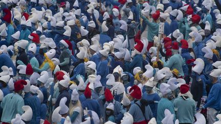 Des personnes habillées en Grand Schtroumpf (avec un chapeau rouge) et en Schtroumpfs participant à un rassemblement record de Schtroumpfs à Landerneau, dans l'ouest de la France, le 25 mars 2023. (FRED TANNEAU / AFP)