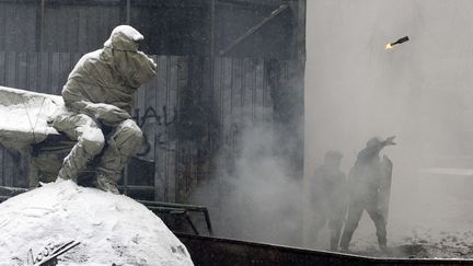 Un policier lance un cocktail molotov, tandis que la place est plong&eacute;e dans l'obscurit&eacute; &agrave; cause de la fum&eacute;e. (DARKO VOJINOVIC / AP / SIPA)