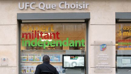 Un passant regarde l'une des vitres des locaux de l'association de consommateurs UFC-Que Choisir&nbsp;à Paris. (JACQUES DEMARTHON / AFP)