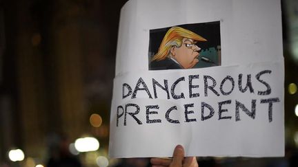 Un homme tient une pancarte "Dangereux Précédent" à l'effigie de Donald Trump lors d'une manifestation à Philadelphie, le lundi 14 novembre.&nbsp; (MARK MAKELA / REUTERS)