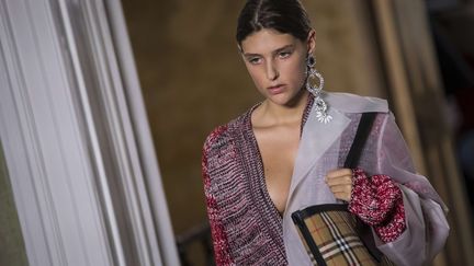 Burberry a donné un coup de jeune à ses classiques. Serait-ce déjà l'effet Marco Gobbetti, l'ex-PDG de Céline qui a pris récemment les commandes pour relancer le groupe confronté à des difficultés ? La collection de la marque britannique a fait montre d'audace et de fantaisie, preuve qu'il est possible d'incarner la quintessence de l'élégance à l'anglaise sans rester sur ses acquis. Le show a lieu à l'Old Sessions House, un bâtiment du XVIIIe. Ce qui saute aux yeux, c'est le plastique, que Christopher Bailey, le styliste, décline à l'envi en jouant avec les formes et les couleurs. Il y a ce long paletot à capuche en plastique doux, porté avec une veste décontractée en cuir d'agneau et des sandales en cuir doré, cette robe plissée mi-longue en tulle ou cet anorak en plastique souple et ultra-fin porté à même la peau, tranchant avec un kilt en laine tartan. Les plastiques sont translucides et colorés : il y a du jaune antique, du rose et du turquoise. Bailey use aussi de la dentelle, dont il orne des jupes longues et sensuelles, et pioche dans le streetwear avec des casquettes de baseball à motif "check", ce tartan beige, blanc, noir et rouge apparu en 1924 et devenu depuis l'emblème de la marque.
 (Vianney Le Caer/AP/SIPA)