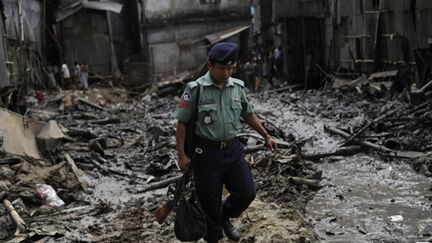 Un policier dans les ruines de l'incendie qui a détruit une partie du site historique de Dacca, le 03 juin 2010 (AFP/MUNIR UZ ZAMAN)