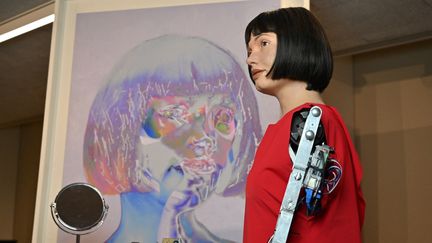 L'artiste-robot Ai-Da et son autoportrait lors d'une exposition au Design Museum de Londres, le 14 mai 2021. (GLYN KIRK / AFP)