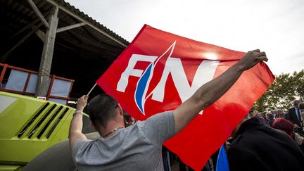 Un homme brandit un drapeau Front national lors d'un meeting de Marine Le Pen, le 30 mars 2017 à&nbsp;Trinité-Porhoët (Morbihan).&nbsp; (MARTIN BERTRAND / AFP)