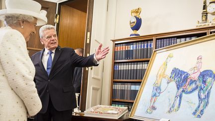 La reine Elizabeth II d'Angleterre découvre le tableau de l'artiste allemande Nicole Leidenfrost que lui présente le président allemand Joachim Gauck, à Berlin (24 juin 2015)
 (Jesco Denzel / BPA / AFP)