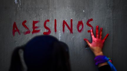 Une&nbsp;femme imprime la marque de sa main sur un mur lors d'une manifestation pour l'élimination des violences faites aux femmes, le 2 mars 2021 à Mexico City (Mexique). (PEDRO PARDO / AFP)