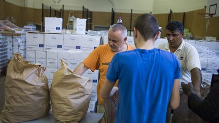 Des membres de l'association Août secours alimentaire donnent des sacs de denrées à des&nbsp;personnes en situation de précarité, le 7 août 2014 à Paris. &nbsp; (FRED DUFOUR / AFP)