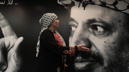 Une femme palestienne passe devant une image de Yasser Arafat, le 10 novembre 2013, &agrave; Ramallah. ( MAXPPP)