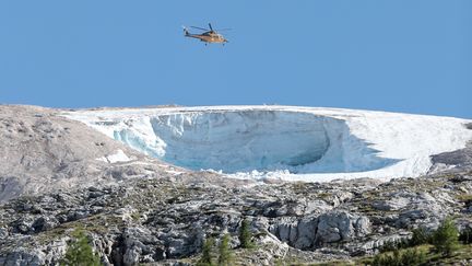 Un hélicoptère de la "Guardia di Finanzia" survole le glacier de la Marmolada, le 4 juillet 2022, un jour après l'effondrement d'un sérac de glace qui a tué sept personnes. (PIERRE TEYSSOT / AFP)