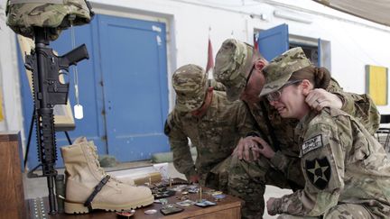 Des soldats am&eacute;ricains se recueillent devant un autel &agrave; la m&eacute;moire d'un de leur compagnon tu&eacute; dans un attentat suicide pr&egrave;s de Kandahar&nbsp;(Afghanistan), le 19 octobre 2012. (ERIK DE CASTRO / REUTERS)