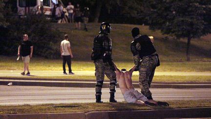 Des policiers emmènent un manifestant, le 9 août 2020, à Minsk. (SIARHEI LESKIEC / AFP)