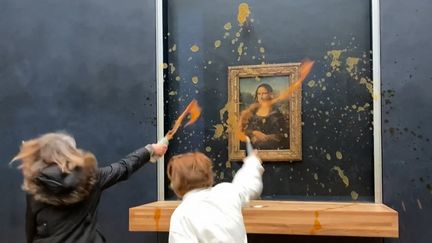 Deux militantes écologistes aspergent de soupe la vitrine qui protège  "La Joconde" de Léonard de Vinci, au Louvre, le 28 janvier 2024. (DAVID CANTINIAUX / AFPTV)