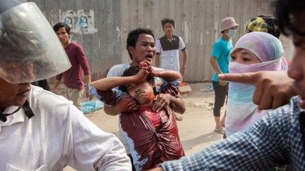 Phnom Penh, au Cambodge, le 3 janvier 2013. Des manifestants transportent un travailleur du textile blessé lors d'affrontements avec la police militaire. Cette dernière a ouvert le feu sur les protestataires. (AFP PHOTO / THOMAS CRISTOFOLETTI)