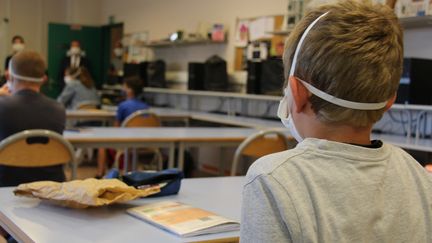 Enfant avec son masque de protection contre le Covid-19 dans une salle de classe. (Claire Leys/Radio France)