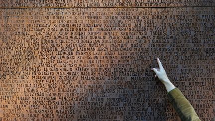 Un homme indique le nom d'un membre de sa famille tué au Monument dédié aux officiers polonais assassinés lors du massacre de Katyn en 1940, à Kharkiv, le 25 septembre 2010. (SERGEI SUPINSKY / AFP)