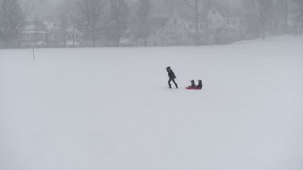 Le meilleur moyen de transports reste peut-être la luge, idéale pour promener les enfants, comme le fait cette femme dans le Connecticut. (TIMOTHY A. CLARY / AFP)