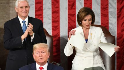 Le vice-président américain Mike Pence (à gauche) debout à côté de la cheffe de file des démocrates à la Chambre des représentants Nancy Pelosi (à droite) qui déchire une copie du discours sur l'état de l'Union de Donald Trump, aux Etats-Unis, le 4 février 2020.&nbsp; (MANDEL NGAN / AFP)