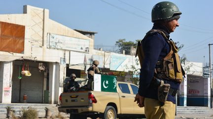 Un policier (à droite) et des soldats de l'armée (à gauche) montent la garde le long d'une route à Bannu, au Pakistan, le 21 décembre 2022. (KARIM ULLAH / AFP)