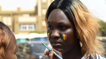 Une jeune supportrice de l'équipe du Sénégal se fait peindre les couleurs nationales pour assister au match contre la Pologne place de l'Obélisque à Dakar. (SEYLLOU / AFP)