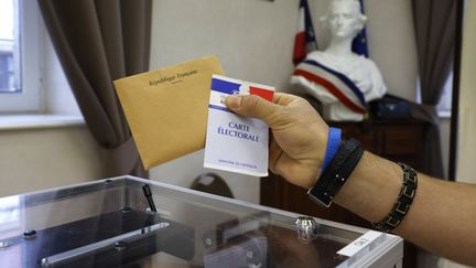 Un électeur dépose un bulletin de vote dans une urne, en juin 2021. (Photo d'illustration) (LUDOVIC MARIN / AFP)