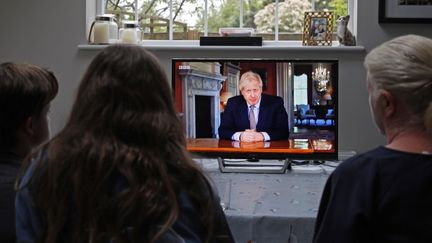 Une famille de Londres regarde en direct l'allocution du Premier ministre britannique Boris Johnson, le 10 mai 2020. (ADRIAN DENNIS / AFP)