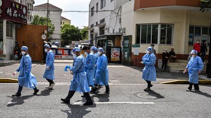 Des travailleurs après avoir déposé des colis alimentaires dans un quartier confiné de Shanghai (Chine), le 25 mai 2022.&nbsp; (HECTOR RETAMAL / AFP)