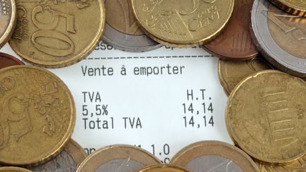 Un ticket de caisse entouré de pièces de monnaie. (RICHARD VILLALON / MAXPPP)