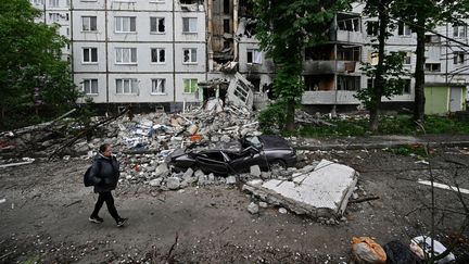 Une femme marche dans un quartier dévasté du nord de Kharkiv (Ukraine), le 29 mai 2022. (GENYA SAVILOV / AFP)