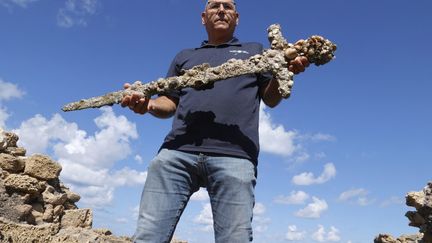 Un responsable de l'Autorité israélienne des Antiquités montre une épée vieille de 900 ans et ayant appartenu à un Croisé à Césarée (Israël), le 19 octobre 2021. (JACK GUEZ / AFP)