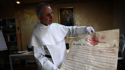 Le père Najeeb Michaeel et un de ses précieux documents
 (SAFIN HAMED / AFP)