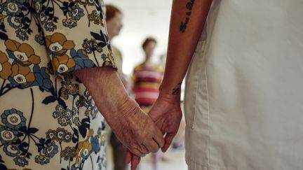 Une enseignante d'art-thérapie tient la main d'une résidente de la "Maison Saint-Jean Hélios", un Ehpad situé à Nice (Alpes-Maritimes), le 4 août 2020. (VALERY HACHE / AFP)