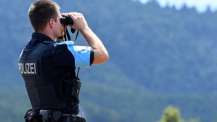 Un membre de l'Agence Frontex regarde à travers des jumelles lors d'une patrouille à la frontière albano-grecque le 4 septembre 2019. (GENT SHKULLAKU / AFP)