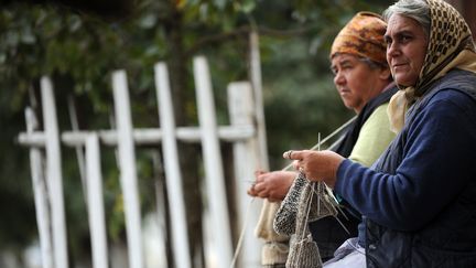 Deux retrait&eacute;es tricotent sur un banc &agrave; Viscri, un village de Transylvanie, en Roumanie. (KARINA KNAPEK / AFP)