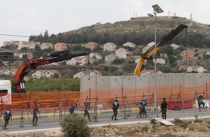 Le mur&nbsp;d'un kilom&egrave;tre, dont la construction&nbsp;a commenc&eacute; en avril 2012, s&eacute;pare notamment Isra&euml;l du village libanais de&nbsp;Kfar Kila, qui surplombe les blocs de b&eacute;ton.&nbsp; (ALI HASHISHO / REUTERS)