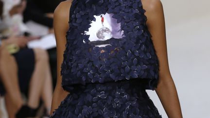 Légèreté, broderies, transparence: trois mots pour résumer la collection de Christian Dior. Raf Simons, le directeur artistique, a fait travailler des brodeurs sur quasiment toutes les silhouettes. Ils ont réalisé fleurs, trèfles et pétales, dans une très grande variété de broderies. "Tout semble léger et simple, même s'il s'agit de la collection la plus complexe jamais réalisée", explique la maison dans une note aux invités. L'écru, et à l'opposé, le bleu encre, dominent la collection. Quand ils ne sont pas transparents, les tissus sont ajourés, comme pour une veste Bar, la célèbre ligne de Dior, avec ses basques qui partent des petites hanches. Raf Simons propose des robes courtes, aux coupes architecturales, bustier ou à bretelles, asymétriques pour certaines. Et il y a les incontournables robes longues du soir, dont des fourreaux. Il a voulu créer une collection "davantage connectée avec notre mode de vie". "J'essaie de faire des habits moins contraignants", "pas de corset rigide". Il est d'ailleurs allé jusqu'à chausser certains mannequins de tennis. "Au fur et à mesure des collections, Raf avance dans la modernité, la nouveauté, tout en gardant l'allure de Dior", a estimé le pdg de Dior Sidney Toledano. 
 (FRANCOIS GUILLOT / AFP)