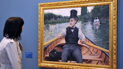 Une visiteuse admire le tableau "La partie de bateau" (1877) de Gustave Caillebotte lors de l'exposition "L'impressionnisme le long de la Seine" à Giverny, le 31 mars 2010. (ROBERT FRANCOIS / FILES)