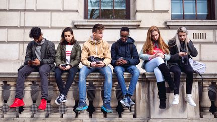 Des adolescents utilisent leurs smartphones, au Royaume-Uni, le 26 février 2017.&nbsp; (LEOPATRIZI / E+ / GETTY IMAGES)